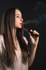 Obraz premium The face of vaping young woman at black studio