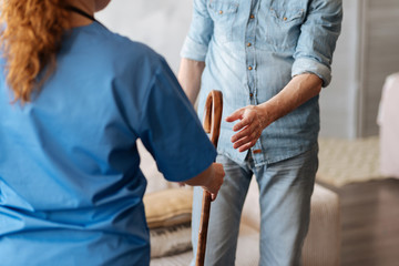 Committed kind medical worker giving her patient a cane