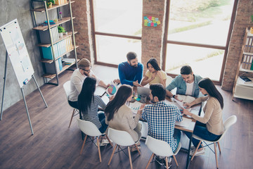 Top view of partners  in casual clothes. They are focused, discussing the ideas for new start-up at nice comfortable  office