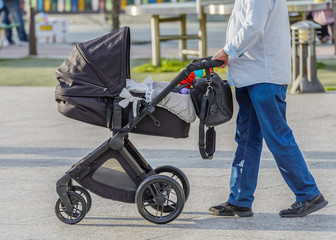 Fototapeta na wymiar man with a baby stroller on a walk