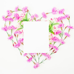 Love symbol made of pink flowers and card on white background. Flat lay, top view.