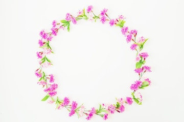 Floral round frame made of pink flowers and leaves on white background. Flat lay, top view.