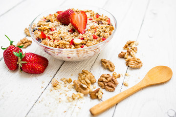 Oatmeal porridge with strawberries, nuts and muesli on white wooden table. Flat lay. Top view.