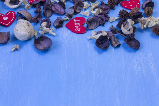 Love celebration background of dried peach roses and wooden carved heart isolated on rustic painted blue table - space for your text