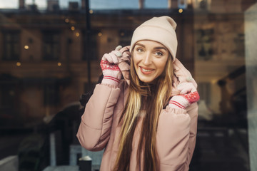 The beautiful girl lovely smiles and holds a collar. On her a pink jacket, a cap and gloves. The girl looks directly at us, she has beautiful long hair.