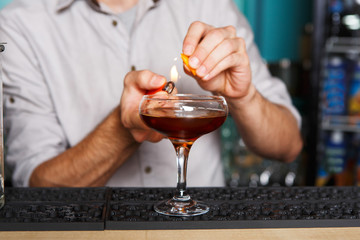 Barman's hands making flaming cocktail