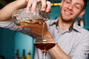Young Barman mixing cosmopolitan cocktail