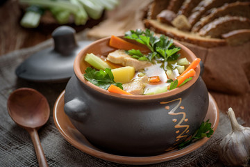 soup in pot, bread, wooden spoon on the table closeup