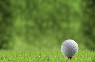 Golf ball and tee on green grass, isolated against the green blurred background.