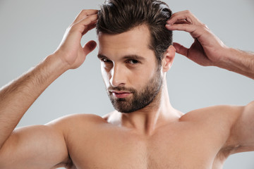 Obraz premium Charming naked bearded man posing and touching his hair