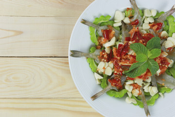 Spicy shrimp salad with fish sauce in white dish.