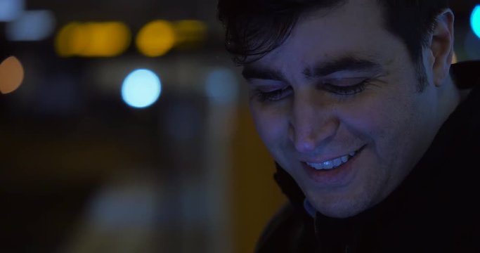 A man looks down and smiles. Orbs of light illuminate the dark background.