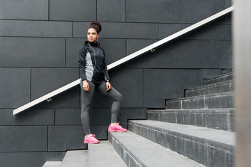 Female jogger resting after running, standing on staircase