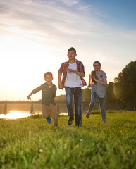Group of happy friends playing catch-up game and running in summer park