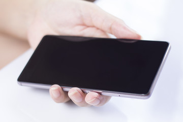 Hand holding mobile smartphone with blank screen.