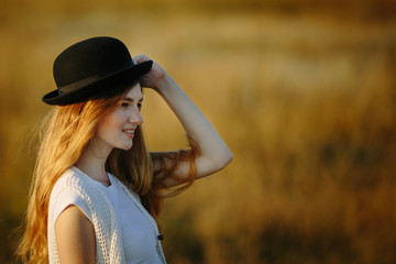 Close up portrait of young pretty woman wearing black hat outdoor on sunset