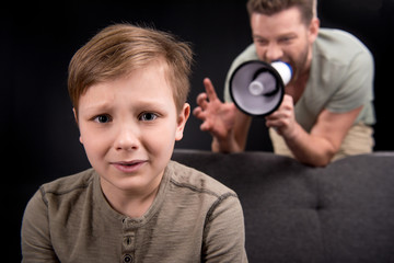 Father with megaphone screaming at scared little son, family problems concept