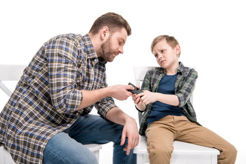 Father and emotional little son quarreling about smartphone, family problems concept