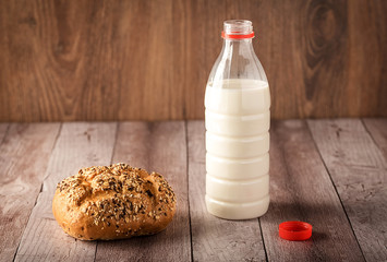 Fresh seedy bread and milk on wooden background