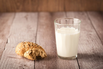 Fresh seedy bread and milk on wooden background