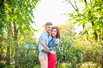 Happy young couple at park standing and laughing on the bright sunny day