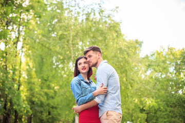 Happy young couple at park standing and laughing on the bright sunny day