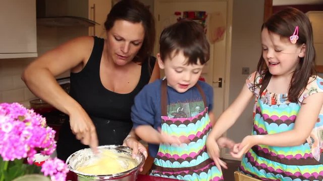 Pregnant mother teacher her children how to bake a cake whilst on maternity leave