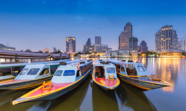 Long tail boat on Chaophraya River in Bangkok with cityscape background.
