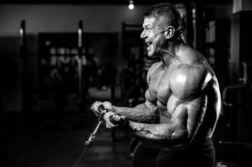 Obraz na płótnie Canvas Brutal strong bodybuilder man pumping up muscles and train gym