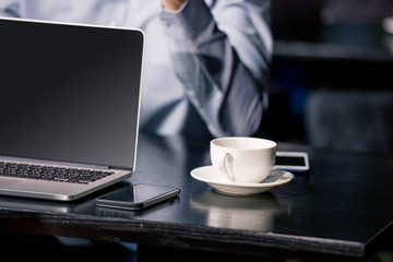 cropped shot of laptop computer, smartphone and cup of coffee in cafe, coffee break concept