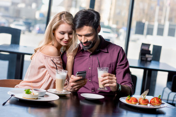 Obraz na płótnie Canvas romantic couple in love using smartphone on coffee break in restaurant