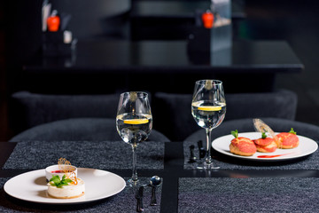close up view of tasty desserts and glasses of water on table in restaurant