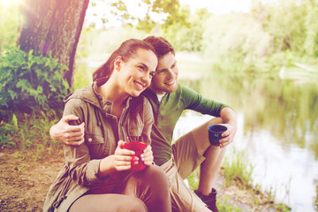 happy couple with cups drinking in nature