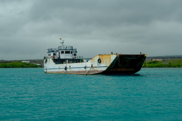 Old Fishing Boat sailing in a beautiful magenta waters in Galapagos in a cloudy day