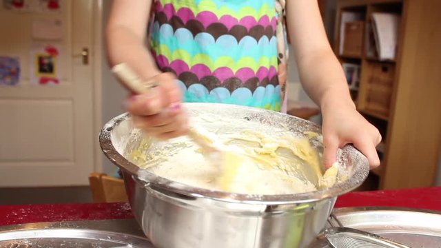 Young child learning how to cook and bake a cake in family home