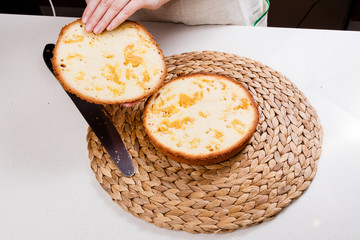 The confectioner cuts the sponge cake with a knife