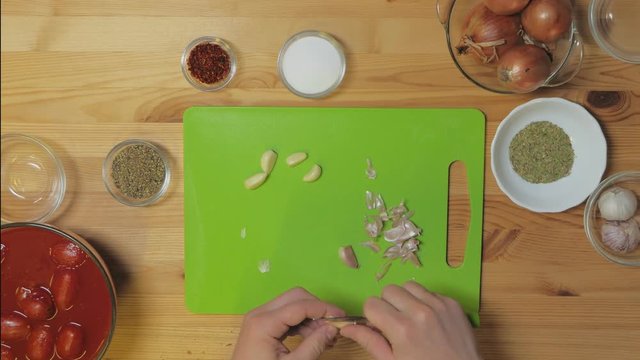 Top view. Male cook on a cutting Board clean and then cut the garlic
