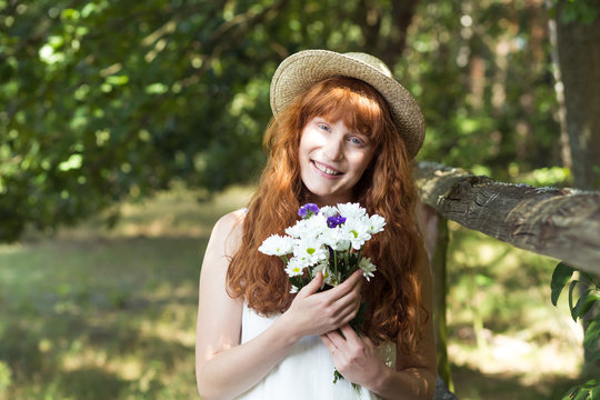 Smiling country girl holding field flowers