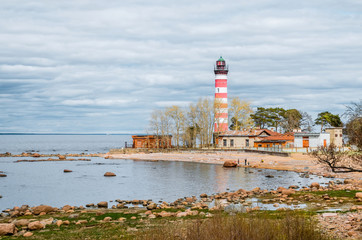 View of the cape on the coast with the old lighthouse in red and white stripes.