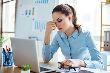 Portrait of tired businesswoman having headache at workplace after working with computer for a long...