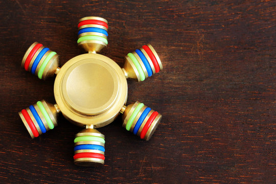 Gold fidget SPINNER stress relieving toy on wooden background. Israel MAY-23-2017.