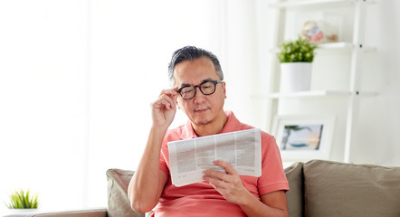 happy man in glasses reading newspaper at home