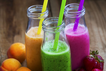 Fresh healthy three types of fruits juices or smoothies, orange, green and pink with strawberries, apricots and kiwi