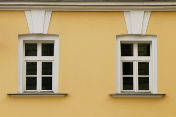 The facade of two windows of a yellow building.