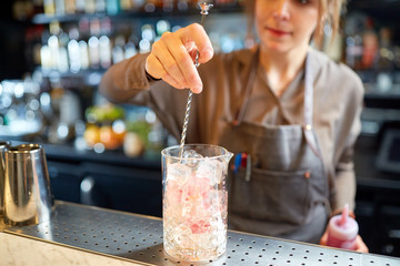 bartender with cocktail stirrer and glass at bar