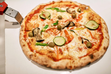 close up of pizza on peel at pizzeria