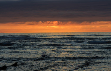 Sunset with rain clouds in the sea. Atmospheric phenomena concept