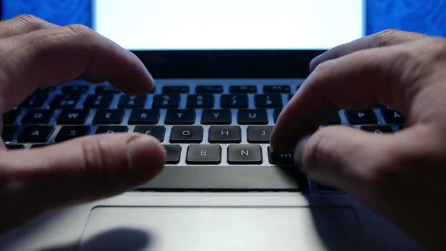 Man typing on laptop keyboard, late night