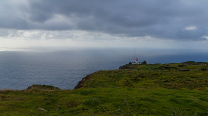 Fototapeta na wymiar Madeira - Ponta do Pargo lighthouse behind green meadows at the coast