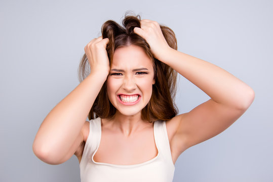 Going crazy and insane. Close up portrait of shouting stressed young girl, messing her hair on pure light background
